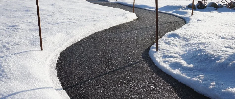 Clear sidewalk in Ada, MI, with snow around it.